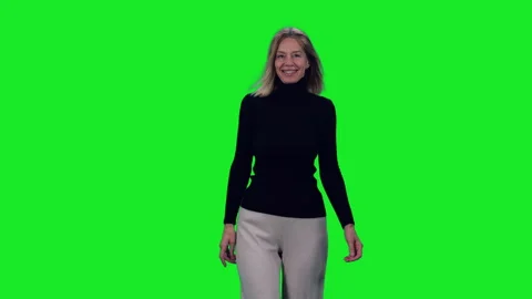 Slow motion of smiling slim mid adult woman walking on green background Stock Footage 297892902