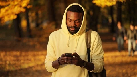 Slow motion smiling young african american attractive man use smartphone walking Stock Footage 100908522