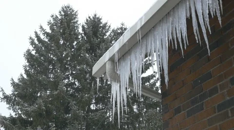 Slow motion snow falling. Icicles hanging from house. Stock Footage 53826735