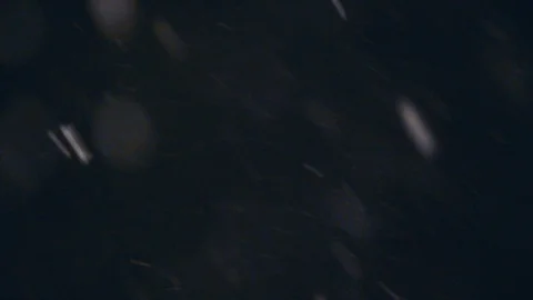 Slow motion snow flurries float by in focus and bokeh during a night blizzard Stock Footage 98379562
