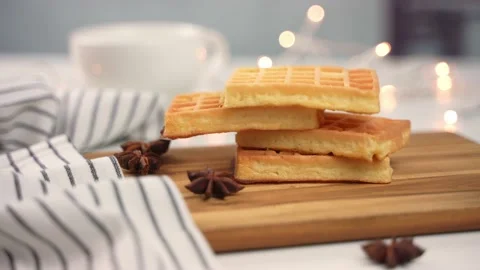 Slow motion of soft waffles falling down next to strings of light. Video stock 168120773
