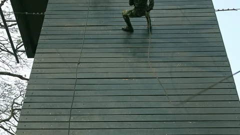 Slow motion of soldiers practice abseiling down a wooden platform. Stock Footage 92304433