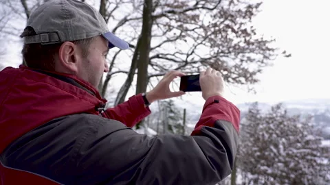 Slow motion of a speaking middle aged man filming cityscape in winter forest. Stock Footage 146949078