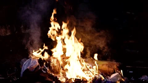 Slow motion speed of flames from burning trash outdoors at night Stock Footage 249143370