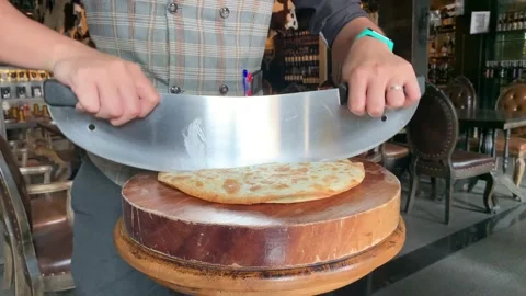 Slow-motion of a Spinach Tortilla pizza being sliced with a semicircular knife. Stock Footage 147640688