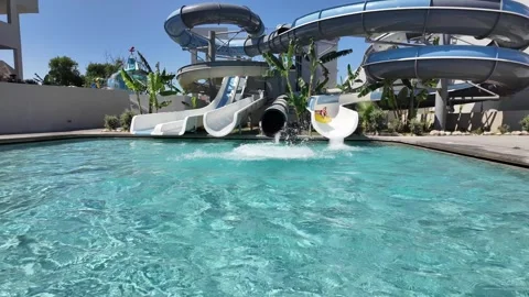 Slow motion splash as guests exit resort water slides into swimming pool. Stock Footage 339490814