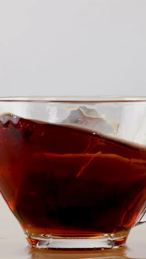 Slow Motion Splash of Tea Bag Dropping into Glass Cup Stock Footage 341733425