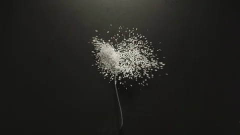 SLOW MOTION: Spoon with coarse sea salt grains falling onto a black table Vidéo 107932532