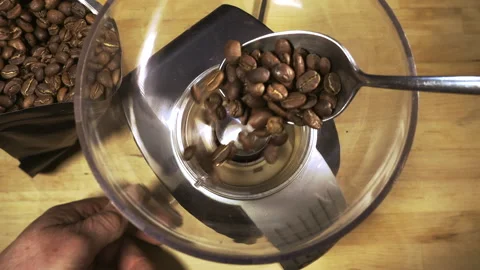 Slow motion - Spoonful of coffee beans placed into a grinder and switched on. Video stock 107313225