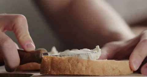 Slow motion spread cream cheese on fresh ciabatta slice on olive board closeup Video stock 163101069