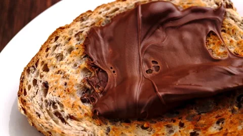 Slow motion spreading of chocolate hazelnut butter on whole wheat toast Stock Footage 47003065