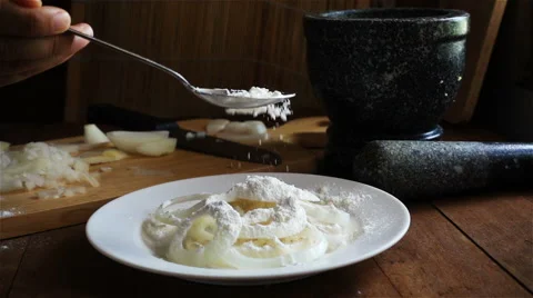 Slow motion of sprinkling the flour with a small spoon on the onion dish Stock Footage 65826558