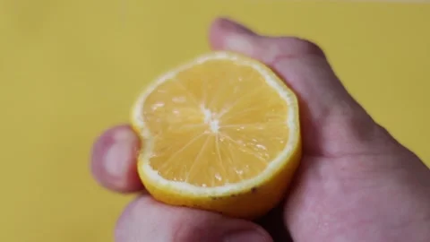 Slow Motion squeeze juice from lemon, hand squeezes half yellow lemon. Stock Footage 131842619