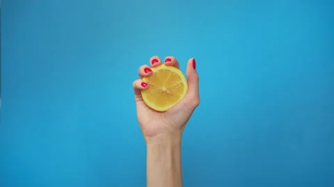 Slow Motion squeeze juice from lemon, close up woman hand squeezes half yellow Video stock 136633339