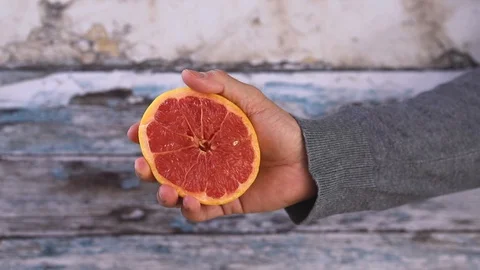 Slow Motion squeezed grapefruit juice, hand squeezes half grapefruit. closi Stock Footage 128896506