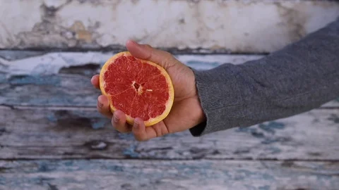 Slow Motion squeezed grapefruit juice, hand squeezes half yellow lemon. closi Stock Footage 128897024
