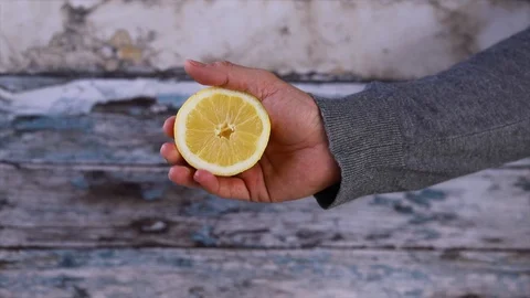 Slow Motion squeezed lemon juice, hand squeezes half yellow lemon. closing. S Stock Footage 128896533