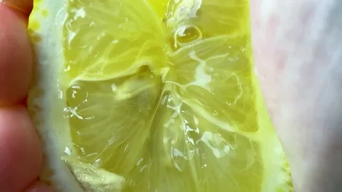 Slow motion squeezing juice from a lemon, hand squeezing half of a yellow lemon Stock Footage 234454017