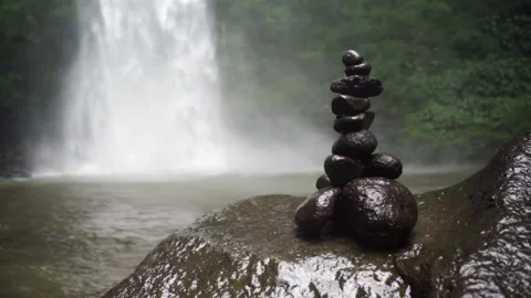 Slow Motion: Stacked River Rocks at the Base of Rushing Waterfall - Bali, Indone Stock Footage 149636674