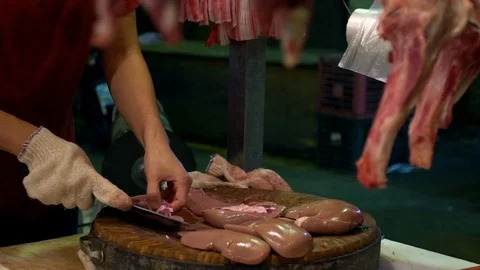 Slow motion stall vendor using knife to cut pieces raw kidney pork on board.-Dan Stock Footage 104404258