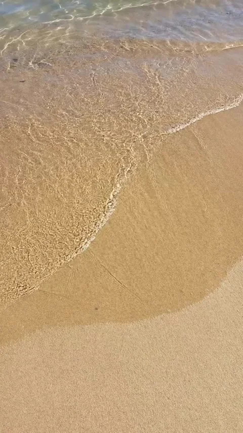 Slow motion static shot of gentle waves washing over sandy beach shore from.. Stock Footage 329871186