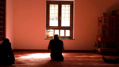 Slow Motion Static Shot of Man Praying in Mosque with Red Light Reflections Stock Footage 327863533