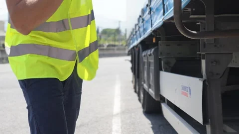 Slow motion static shot of Worker in Hi-Vis Vest turns a lever on a trailer Stock Footage 336777515
