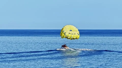 Slow motion static shot of yellow parasailing parachute towed by speedboat on Vídeos de archivo 331931987