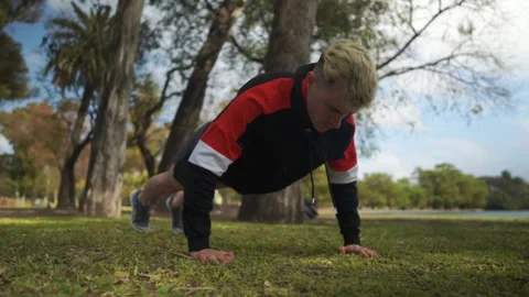 Slow motion static shot of a young man doing push ups at park Stock-Footage 140551370