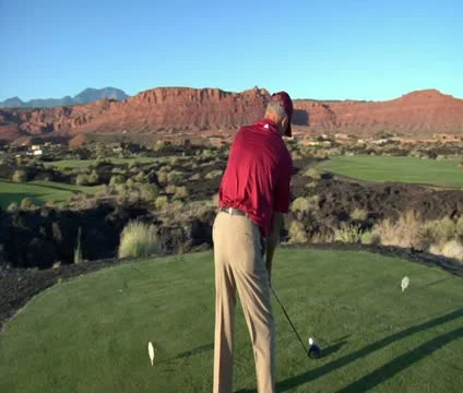 Slow-motion  steadicam shot of man teeing off on golf course with sunset and red Stock Footage