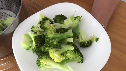 Slow motion Steamed broccoli, picking from a pot on a white plate. Stock Footage 132780090