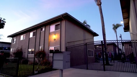 Slow Motion Still Apartment Complex Evening with People walking in front Stock Footage 92402865