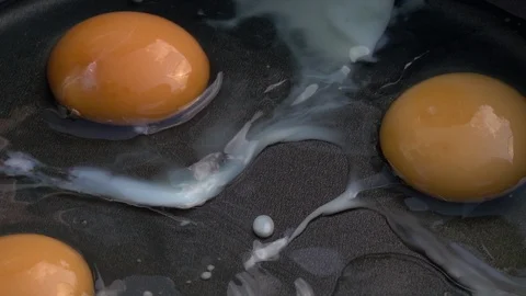 Slow motion of stirring fresh eggs with transparent albumen and whole yolk. Stock Footage 99850733