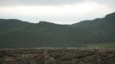 Slow motion stone wall scene of rain with defocused mountains in the background Stock Footage 171633055