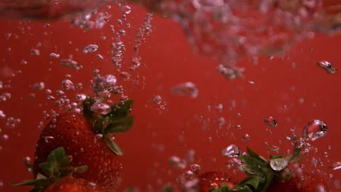 Slow Motion of Strawberries Falling Into Water with a Red Backdrop Stock Footage 270406497