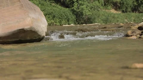 Slow motion stream with boulder in distance Stock Footage 139930771
