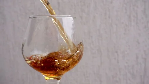 Slow motion a stream of brandy pours into a wine glass. Stock Footage 122494891