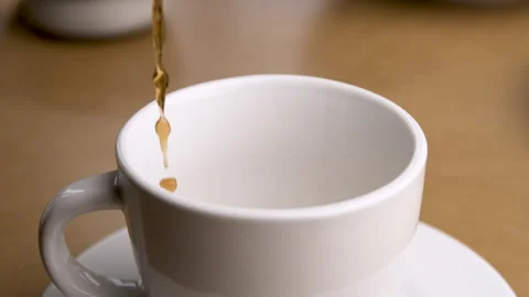 Slow Motion of a Stream of Coffee Pouring Into an Empty Tea Cup Stock Footage 270386098