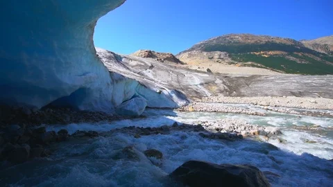 Slow Motion of Stream Flowing Over Rocks Out Of Glacier Cave, Sunny Mountains 스톡 동영상 113948727
