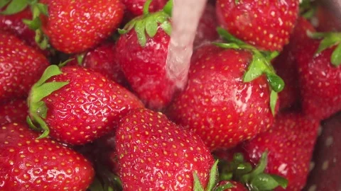 Slow motion a stream of water pours onto a strawberry in a colander Video stock 90257153