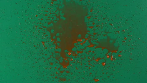 Slow motion. Streams of red paint fall into the center of a green background and 库存影片 168570582