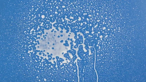 Slow motion. Streams of white paint fall into the center of a blue background 库存影片 169433319