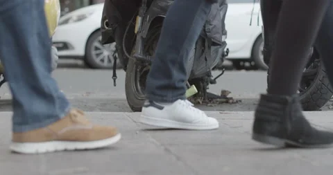 Slow motion street level pan of sidewalk showing feet of pedestrians, scooter Stock Footage 169718659