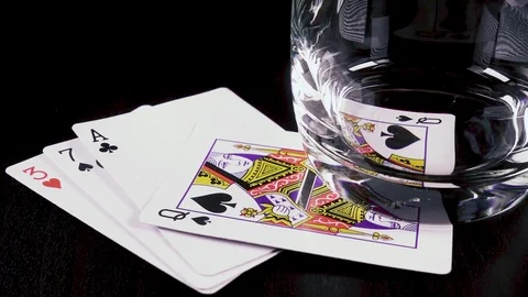 Slow motion strong alcoholic drink pour into a glass and playing cards Stock Footage 92541068