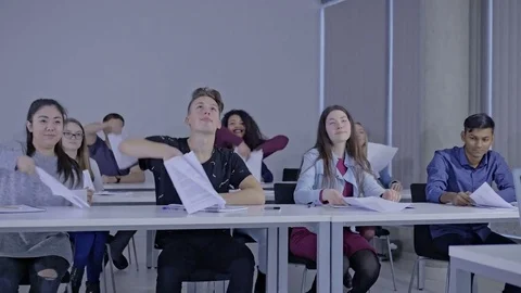 Slow motion of students throwing the sheets of paper up during the class Stock Footage 74616451