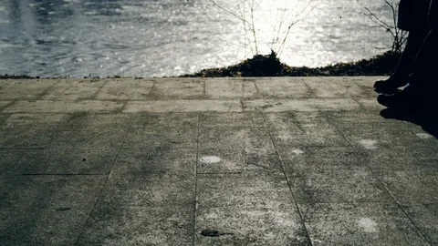 Slow motion: Sun casts shadows of people walking on the waterfront. 4k. Видео 103473955