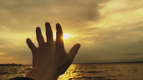 SLOW MOTION. Sun rays emerging through hand on background exotic sea Video stock 117273781