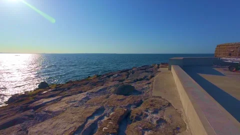 Slow motion sun shining brightly over sea horizon on rocky coast Stock Footage 340452308