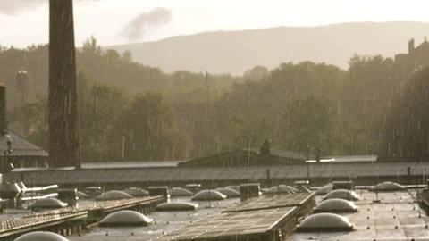 Slow motion sun shower rain over an industrial rooftop at sunset Stock Footage 324660511