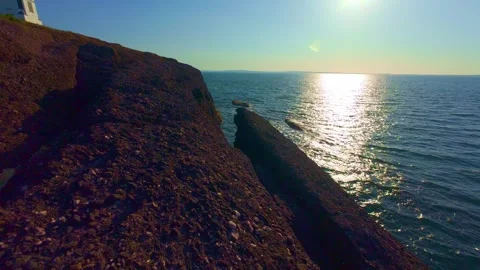 Slow motion sunlit coastal cliffs and calm blue ocean water Stock Footage 340451807
